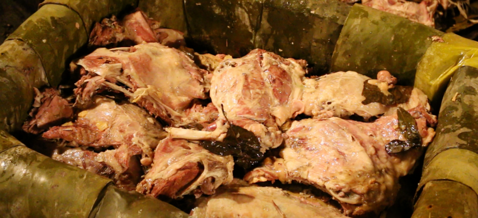 Proceso de cocción de la pancita de barbacoa en un horno de tierra, envuelta en pencas de maguey.