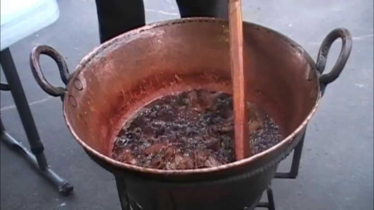 Un cazo de cobre con chicharrón friéndose, mostrando el origen de qué es el asiento de puerco.