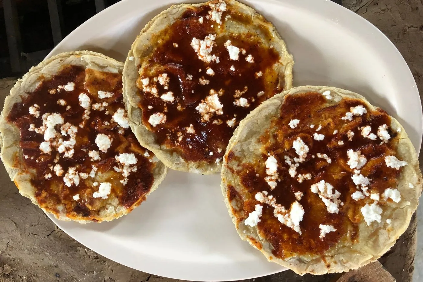 Una tlayuda oaxaqueña siendo preparada, destacando la capa de asiento de puerco sobre la tortilla.