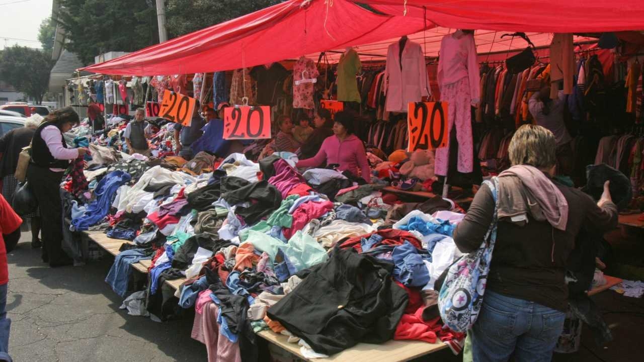 Montañas de ropa en el tianguis de paca de lujo El Rosario, con letreros de precios bajos.