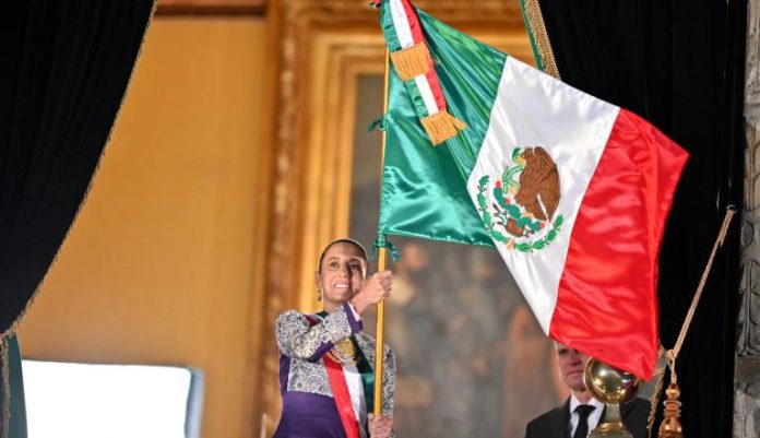 Claudia Sheinbaum ondeando la bandera de México en su primer Grito de Independencia, un momento histórico.