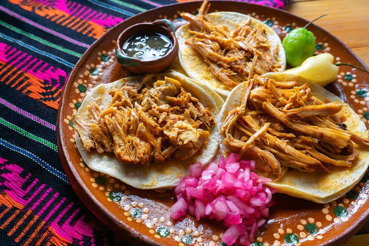 Tacos de cochinita pibil con cebolla morada curtida y chile habanero, un platillo yucateco popular.