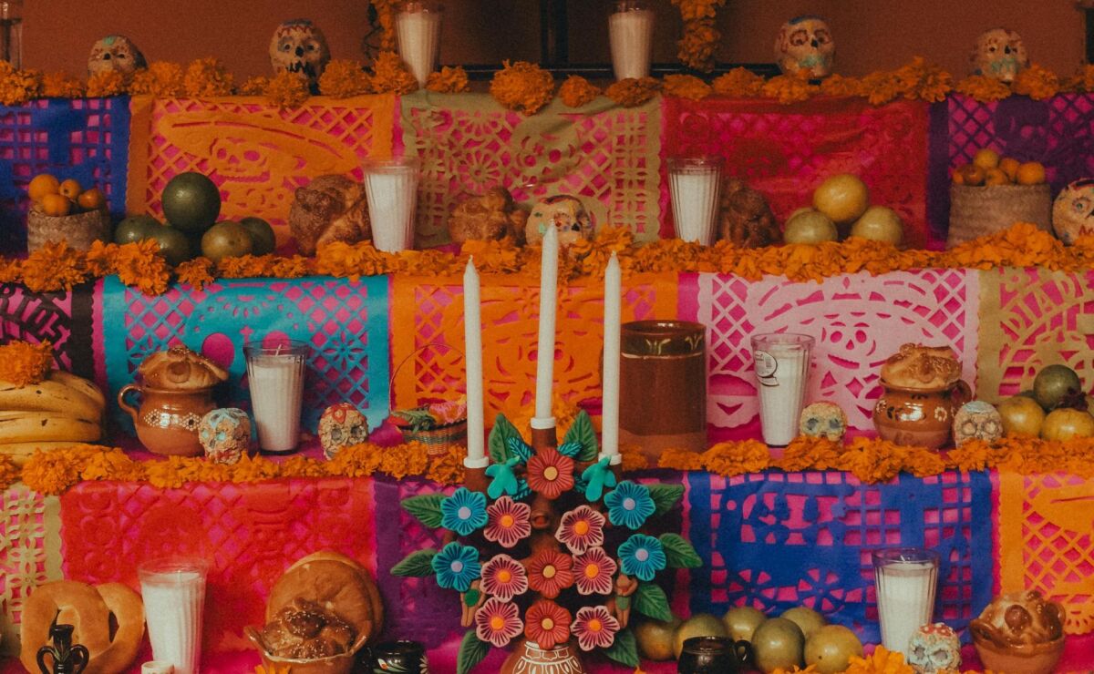 Primer plano de una ofrenda con papel picado y una densa capa de flores de cempasúchil, mostrando elementos esenciales del altar de muertos.