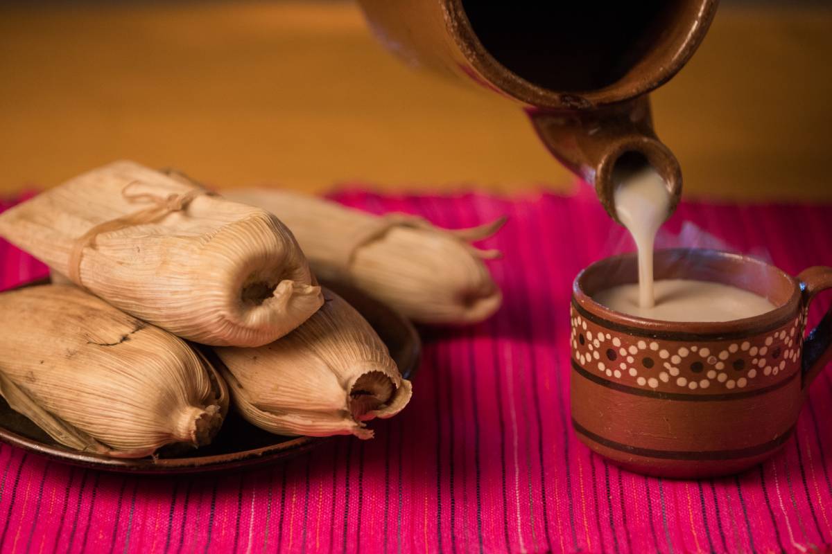 Mesa servida con tamales y ponche navideño, platillos típicos para saber cómo organizar una posada navideña.