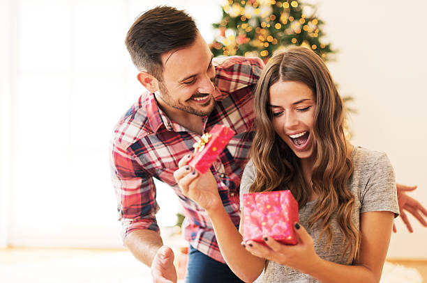 Pareja sorprendiéndose con regalos en Navidad