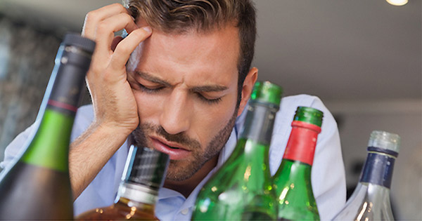 Persona con dolor de cabeza, bebiendo agua, ilustrando la búsqueda de curas para la resaca.