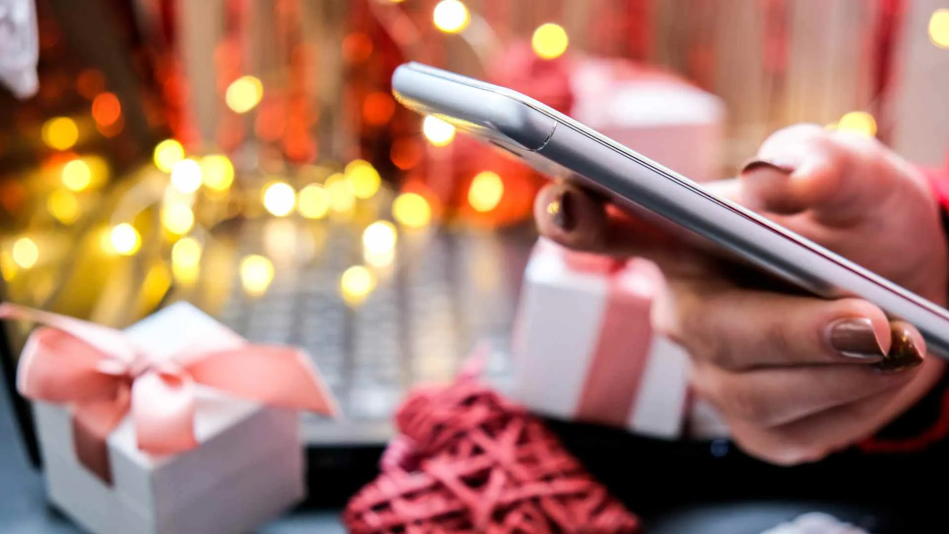 Persona usando una app en su móvil para organizar el Amigo Invisible, con motivos navideños de fondo.