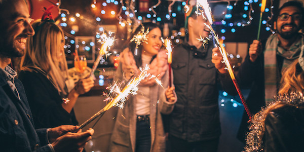 Personas en una posada tradicional mexicana cantando con velas y farolillos, una tradición clave de la Navidad en CDMX.