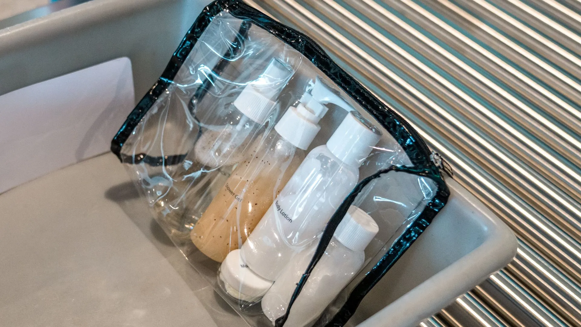 Bolsa transparente con envases de líquidos de 100ml en un control de seguridad de aeropuerto, representando las reglas de líquidos en el avión 2026.