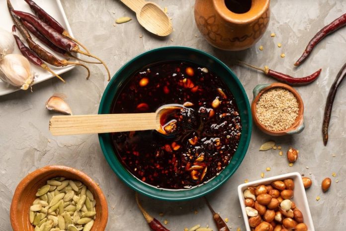 Frasco de salsa macha con cacahuates y arándanos, lista para guardar y usar en tus platillos.