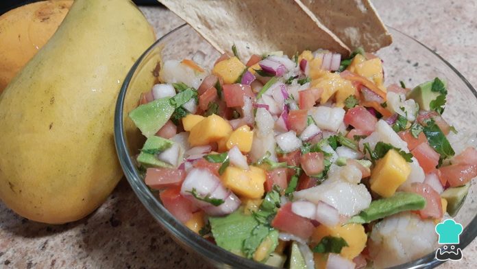 Ingredientes frescos para la receta de ceviche de mango- pescado, limones, mango, cebolla y chiles.