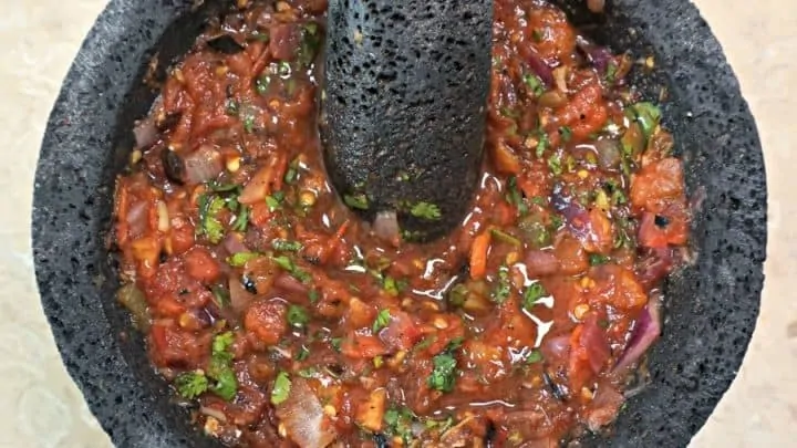 La textura final de la receta de salsa para barbacoa en un molcajete de piedra.