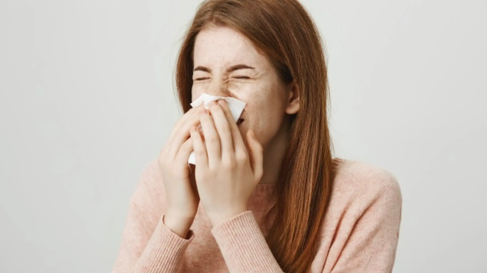 Mujer con congestión nasal, tocándose la nariz con expresión de malestar, buscando remedios caseros.