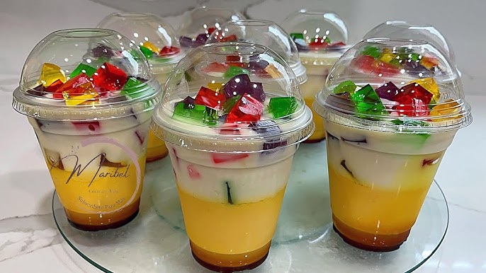 Porciones individuales de gelatina de mosaico tres leches en vasos, decoradas con fruta.