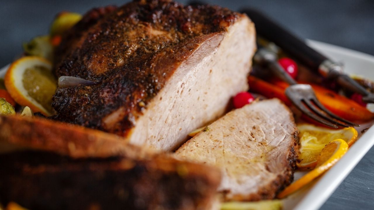 Receta de pierna de cerdo adobada recién salida del horno, con una costra dorada y jugosa.