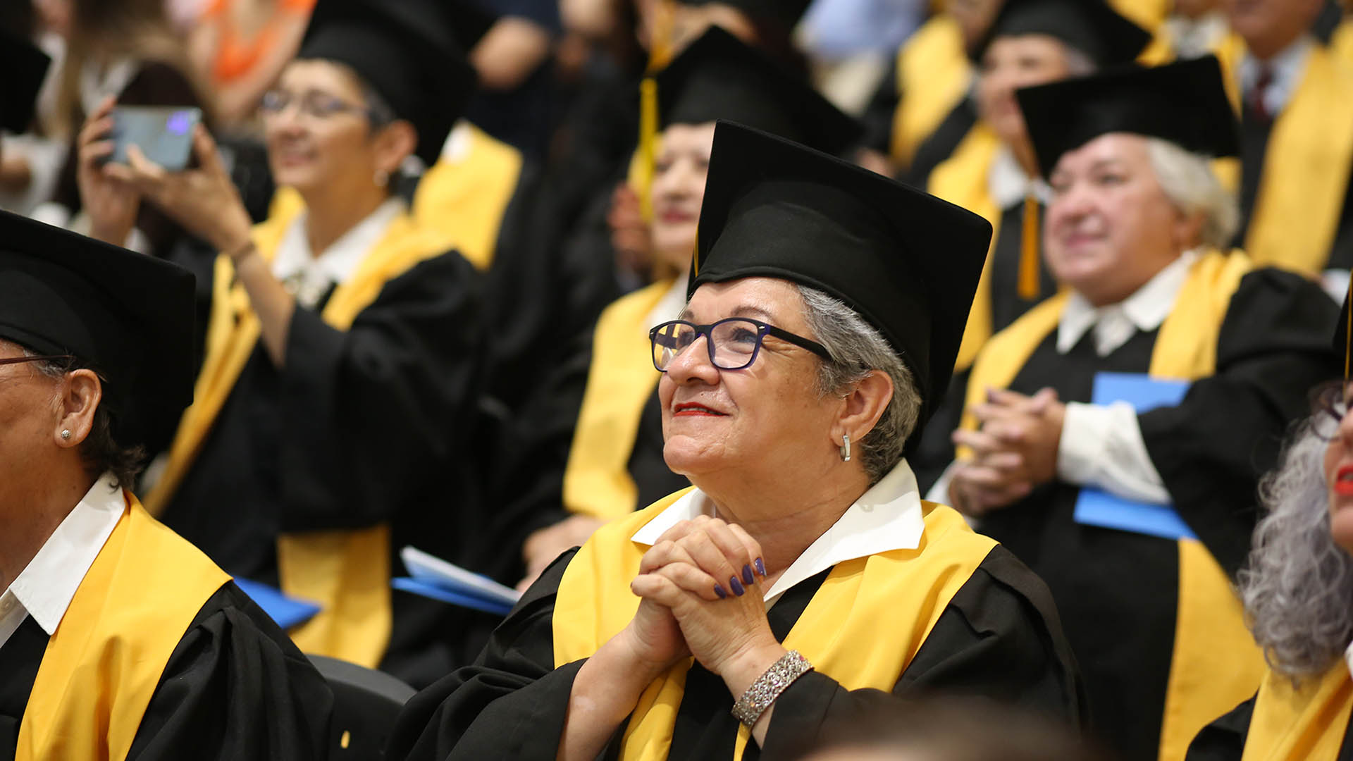 Persona adulta con toga y birrete, celebrando su graduación, gracias a la educación del INEA.
