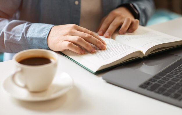 Persona leyendo uno de los mejores libros de crecimiento personal con una taza de café al lado.