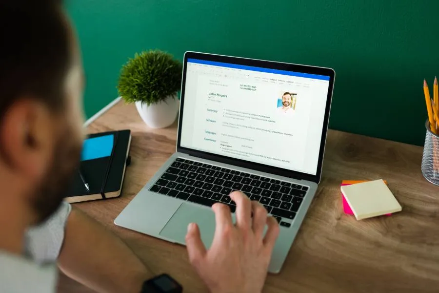 Persona revisando un currículum de impacto en una laptop, listo para aplicar a un nuevo empleo.
