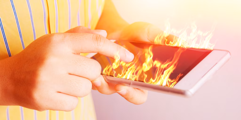 Persona sosteniendo un celular caliente, buscando soluciones para enfriarlo.