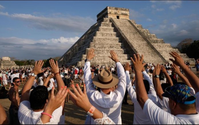 Personas realizando un ritual de brazos abiertos hacia el sol en Teotihuacán, recargando energía durante el equinoccio de primavera.