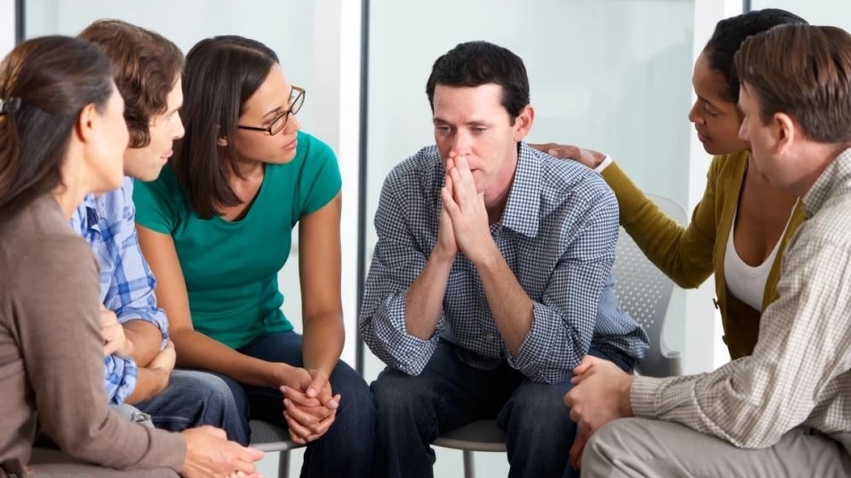 Varias personas interactuando en un grupo de apoyo, simbolizando la importancia de la comunidad para la salud mental.