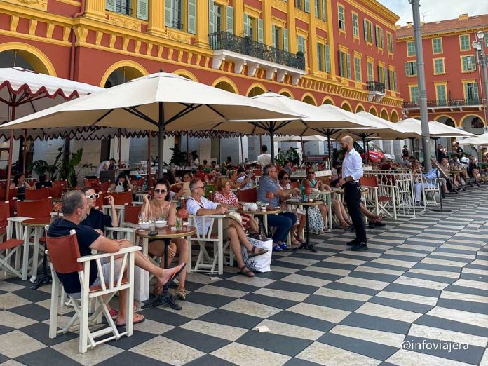 Gente disfrutando en una terraza de un café parisino, simbolizando la calidad de vida y el atractivo para el talento internacional.