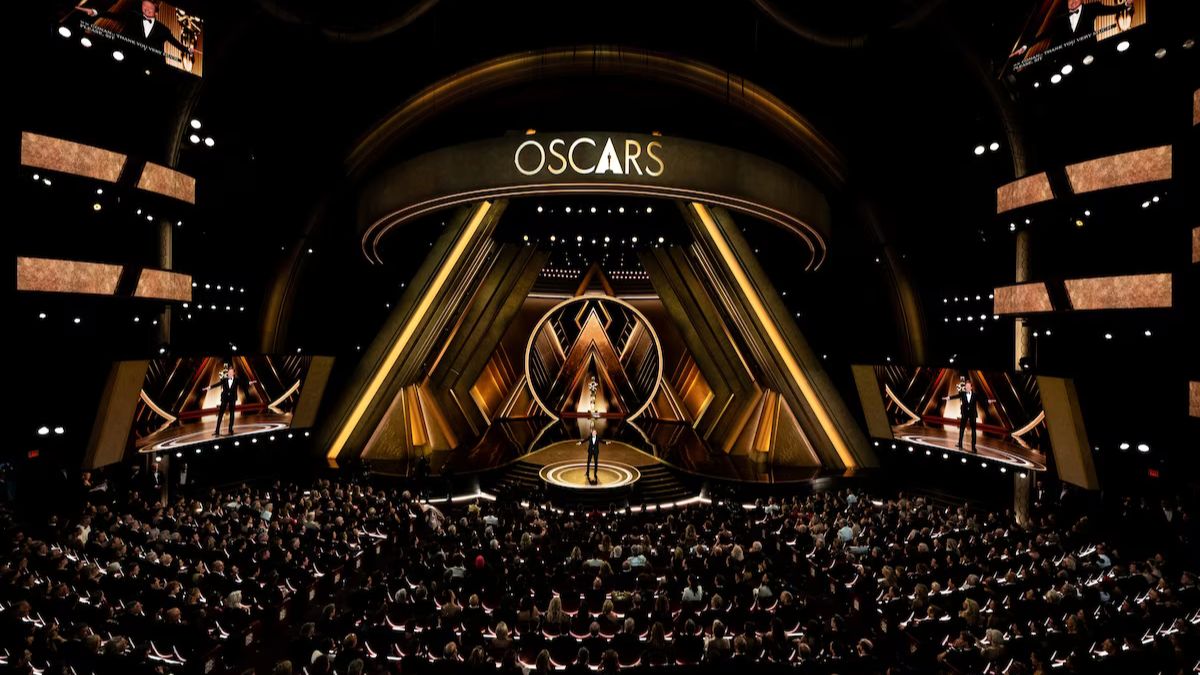 Presentadores anunciando las Nominaciones Premios Oscar 2026 en un escenario con el logo de los Oscar.