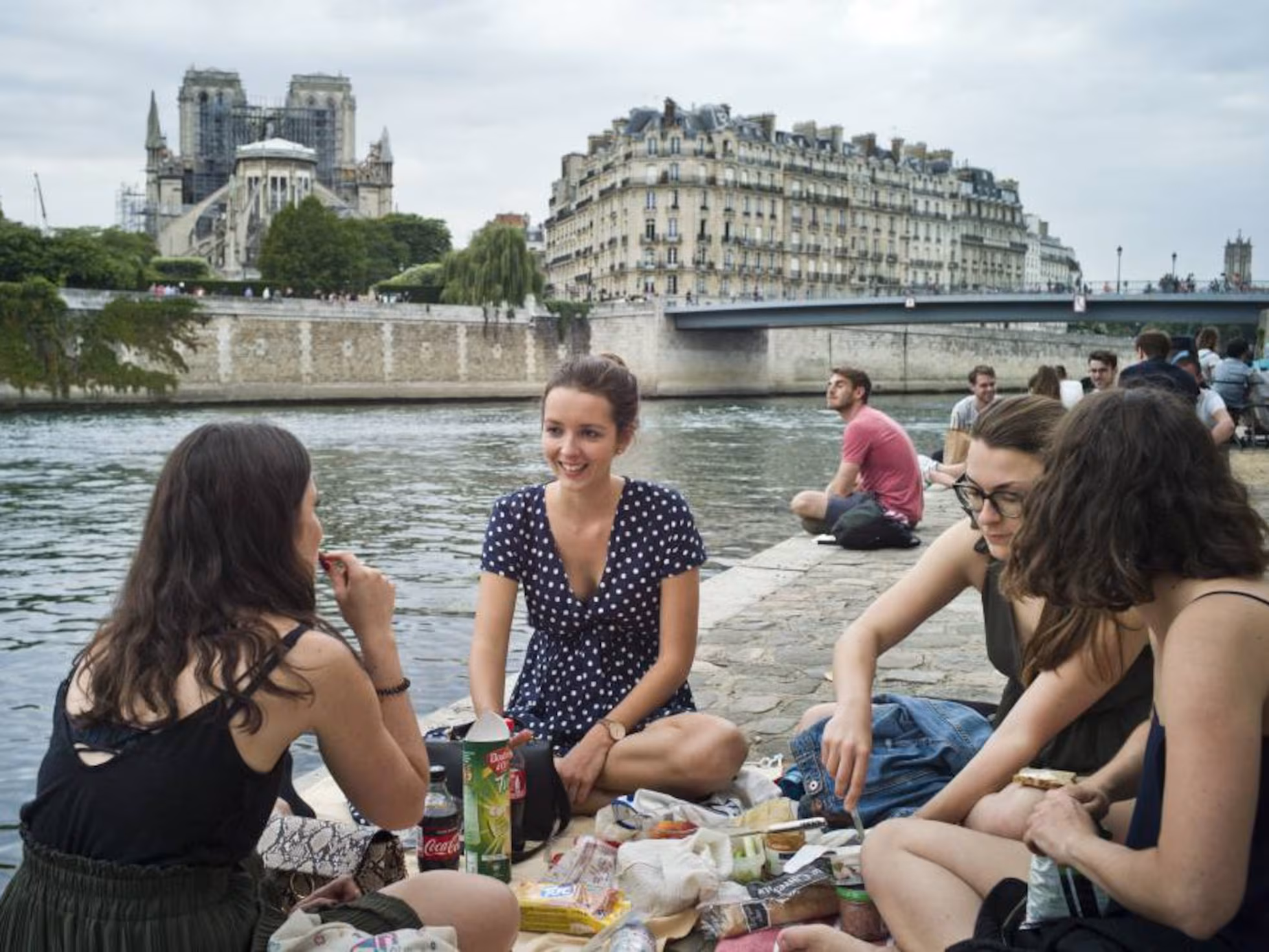 Tumbonas y sombrillas en las playas artificiales en París a orillas del Sena, con monumentos de fondo.