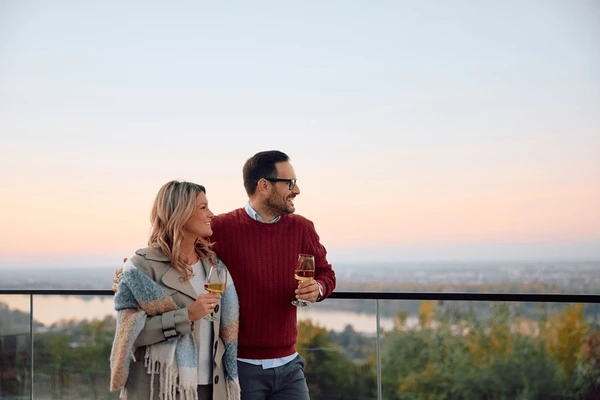 Una pareja feliz disfrutando de una copa de vino en el balcón de su nueva casa en Francia.