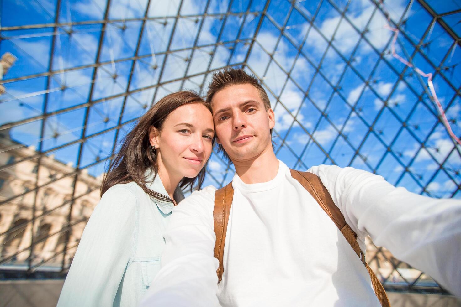 Una pareja feliz tomándose una selfie en París, habiendo conseguido un vuelo barato en temporada baja.