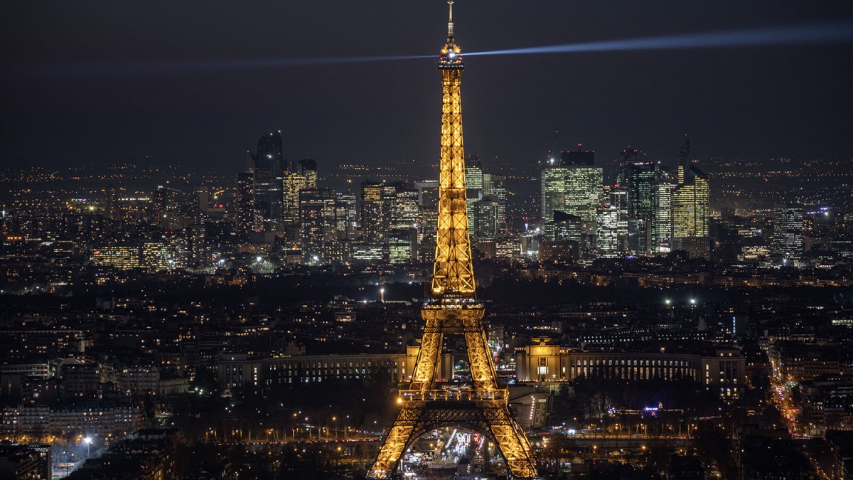 Vista nocturna de la Torre Eiffel desde el Arco del Triunfo, con sus luces brillando.