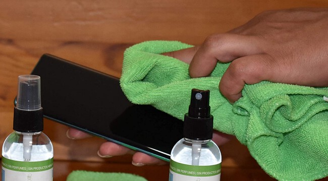 Botella de agua destilada humedeciendo un paño de microfibra, el método correcto para limpiar pantallas.