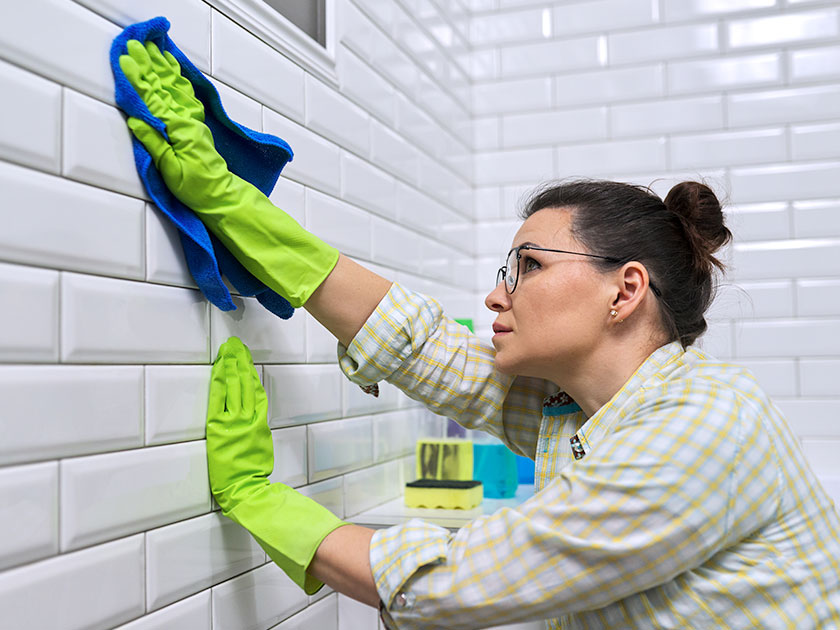 Cepillo de cerdas duras limpiando una junta de azulejo con una mezcla de bicarbonato.
