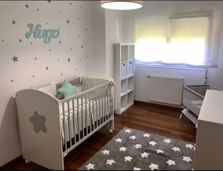 Cuarto de bebé niño con estilo nórdico, paredes grises claras, vinilos de estrellas y cuna de madera natural.