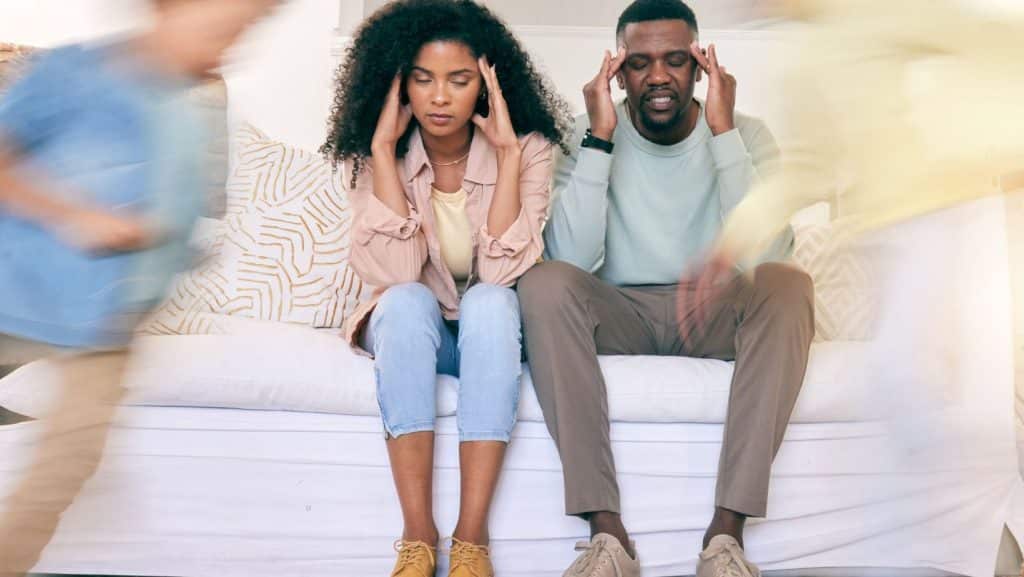 Pareja sentada en un sofá mostrando distanciamiento emocional, una señal psicológica de posible infidelidad.