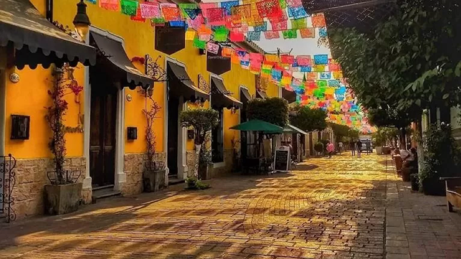 Andador peatonal de Tlaquepaque Jalisco con galerías de arte calles empedradas y árboles decorados con papel picado colorido